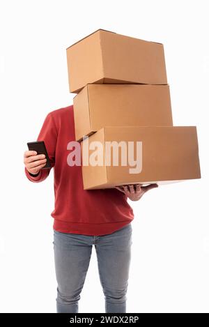Man in red sweater on white background holding large cardboard boxes and using cell phone. Online parcel shipping and delivery service Stock Photo