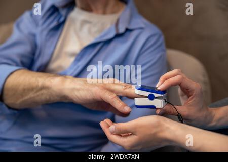 Nurse checking pulse or level of oxygen using oximeter of unrecognizable senior man. Stock Photo