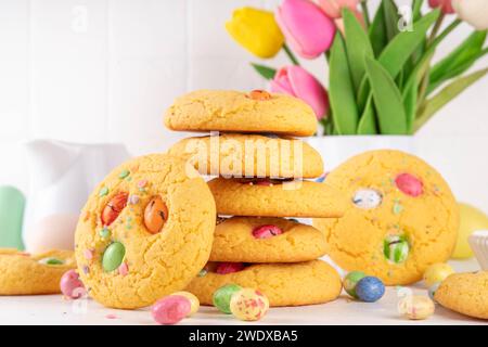Colorful Funfetti chocolate chips mix Cookies. Homemade sweet Easter vanilla biscuits with sugar sprinkles and chocolate Easter eggs, on white kitchen Stock Photo