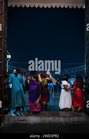 Georgetown, Penang, Malaysia - February 05, 2023: Women with colorful Saris at the temple entrance waiting for the rain to stop at Thaipusam festival Stock Photo