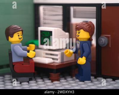 Tambov, Russian Federation - January 21, 2024 A Lego businessperson minifigure sitting behind a computer and talking with another lego businessperson Stock Photo