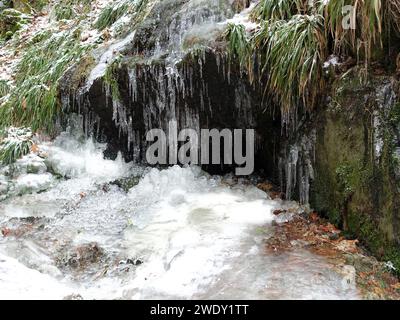 Waterfall with snowy top cascades into water Stock Photo