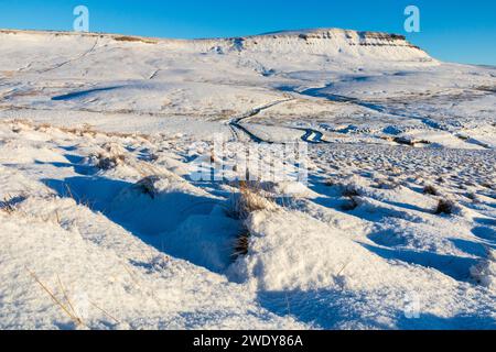 The snow-covered slopes of Pen-y-ghent in the Yorkshire Dales on a winter day in northern England, with clear blue sky and bright sunshine in January. Stock Photo