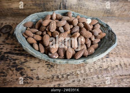 almonds in a ceramic bowl on a wooden background, top view. Stock Photo