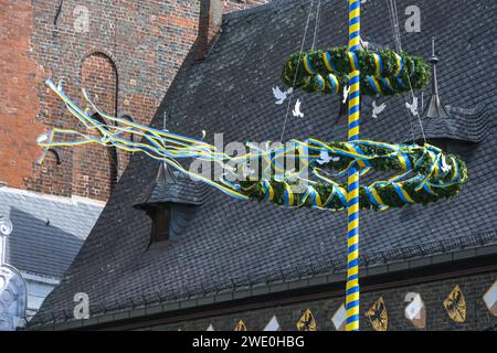 Maypole with white peace doves and fluttering blue yellow ribbons, colors of the Ukraine flag, in front of the town hall of Lubeck, Germany, May 2022, Stock Photo