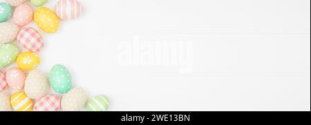 Easter side border with farmhouse style cloth and pastel colored eggs over a white wood background. Top view with copy space. Stock Photo