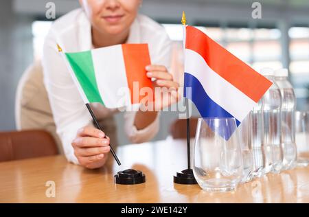 Businesswoman arranging the flags of Italy and Netherlands for presentation and negotiations Stock Photo