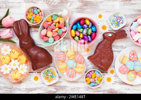 Easter candy table scene. Top down view over a white wood background. Chocolate bunnies, candy eggs and a collection of sweets. Stock Photo