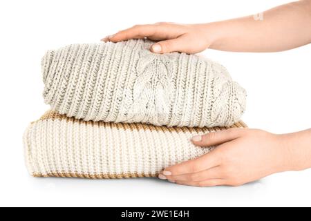 Female hands with stack of different stylish sweaters on white background Stock Photo