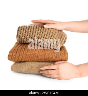 Female hands with stack of different stylish sweaters on white background Stock Photo