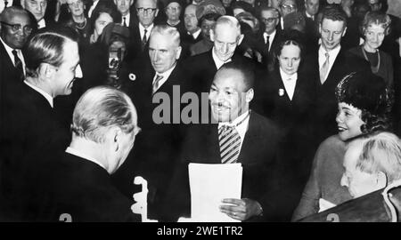 Martin Luther King Jr., winner of the 1964 Nobel Peace Prize, being warmly congratulated by His Royal Highness Crown Prince Harold (left) and His Majesty King Olav V (back to camera) in Oslo, Norway, on December 10, 1964. Dr. King is joined by his wife, Coretta, at his left. Stock Photo