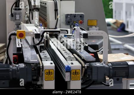 Industrial automated machine at furniture factory. Wood chipboard panels processing. Selective focus. Stock Photo