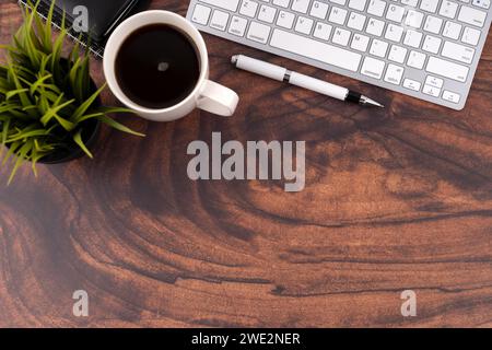 Wooden desk with coffee, pen and computer keyboard flat lay Stock Photo