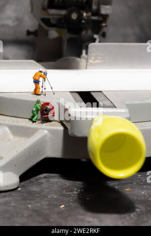 Miniature scale model workers on an electric circular saw.  Construction concept. Stock Photo