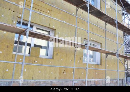 Installing mineral wool insulation over exterior wall for home energy saving. Stock Photo