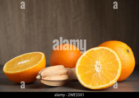 Fresh ripe oranges and reamer on wooden table Stock Photo