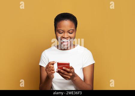 Excited young woman texting on her phone. Happy casual model student using smartphone, messaging or browsing social networks Stock Photo