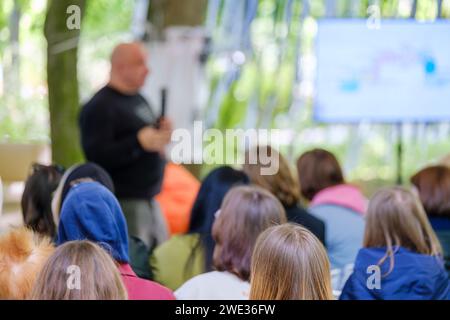 An instructor holding a class in a natural environment, with attentive participants listening. Stock Photo
