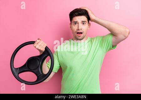 Photo of confused funny man driver holding steering wheel car part after traffic crash accident on road isolated over pink color background Stock Photo