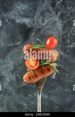 Grilled Sausages with Tomato and Rosemary on Silver Fork Stock Photo