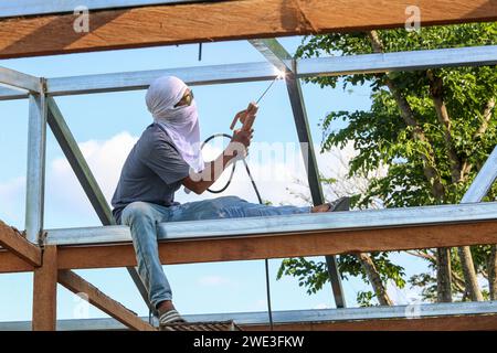 Filipino construction worker welding on roof metal structure of a Bahay ...