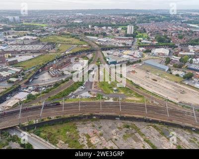 Aerial photograph of a train on the main line in / out of Leeds Station with branch lines off heading to the west, and a disused viaduct and bridge Stock Photo