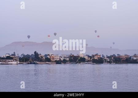 Luxor, Egypt - December 26 2023: Hot air balloons floating over the Nile River in Luxor at sunrise Stock Photo