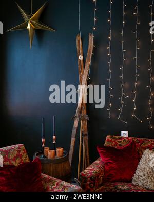 Interior with wooden barrel, old skis, candle with candle stick, decoration. Interior design of christmas. Stock Photo