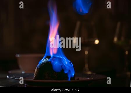 Festive christmas pudding on fire. Flaming English Christmas pudding. Soft focus. Stock Photo