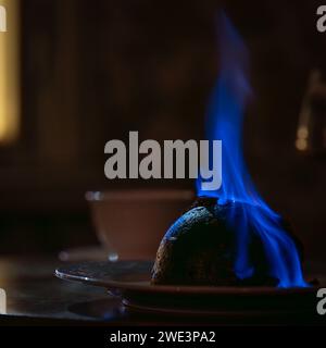 Festive christmas pudding on fire. Flaming English Christmas pudding. Soft focus. Stock Photo