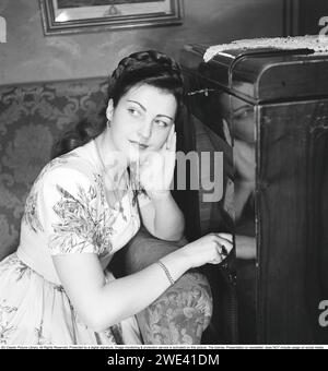 Radio listeners in the 1940s. Inger Juel, 1926-1979, Swedish singer and actress. Here at home listening to a transistor radio and she turns the knob to tune in for a better reception of the radio signal. 1947. Kristoffersson ref AD41-4 Stock Photo