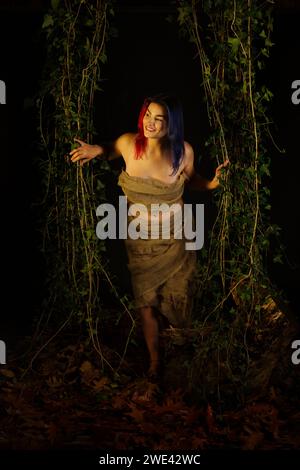 pretty woman peering out through ivy in the woods Stock Photo