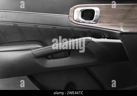 Door handle with power window control buttons of a luxury passenger car. Black perforated leather interior with stitching. Modern car black leather in Stock Photo