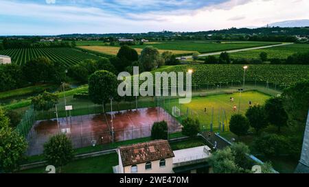 An aerial view of a tennis court surrounded by a lush vineyard, set against a blue sky Stock Photo