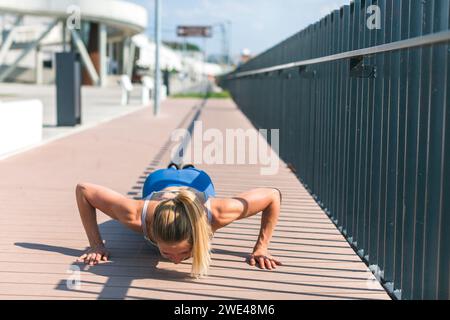 young woman doing pushups outdoors Stock Photo