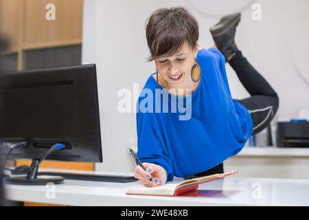 young woman taking notes and stretching in the office Stock Photo