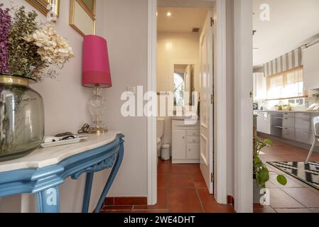 Small modern design bathroom with white wooden furniture with porcelain sink and white wooden framed mirror next to other rooms Stock Photo