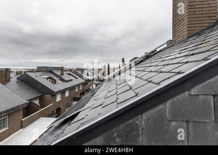 Roofs of a residential neighborhood with black slate tiles and solar panels installed on the roofs Stock Photo