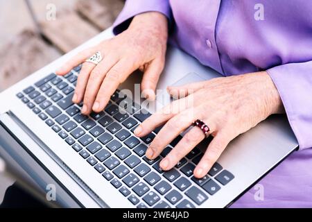hands of a senior woman typing on a laptop Stock Photo
