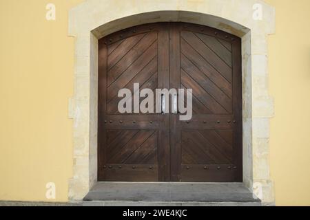 A double brown wooden door set in yellow wall building Stock Photo