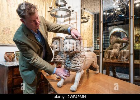 London, UK.  23 January 2024. A staff member examines ‘A pair of continental wooden hand carved lions’, 18th century, on Phil’s Cool Stuff stand at The Decorative Fair at Evolution London in Battersea Park.  Fine and decorative antiques, 20th century design, textiles and objects dating from c1700 to the 1970s, along with works of art of all periods from classical to contemporary are on sale in the show which runs to 28 January 2024.  Credit: Stephen Chung / Alamy Live News Stock Photo