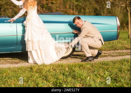 Funny, unusual, stylish, original photos with role reversals of a young, attractive wedding couple with beautiful veteran cars in the nature. Stock Photo