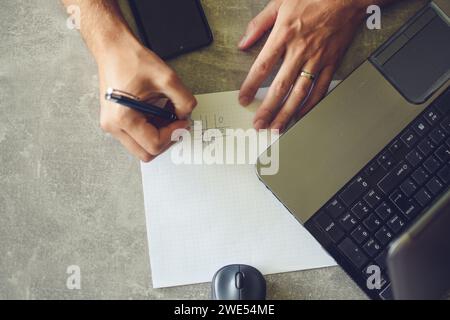 person using laptop, working and taking notes Stock Photo