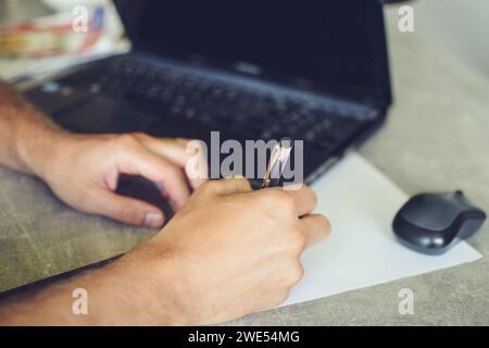 person using laptop, working and taking notes Stock Photo
