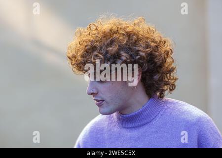 portrait of a young red haired caucasian curly man using v polo neck outdoor winter over solid background beige wall Stock Photo