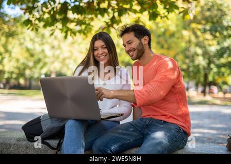 College students using a laptop computer in a park, young people and technology concept Stock Photo