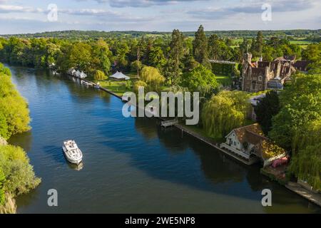 Aerial view of a Le Boat Horizon 4 houseboat passing the Oakley Court Hotel along the River Thames, Water Oakley, near Windsor, Berkshire, England, Un Stock Photo