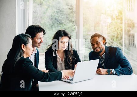 Diverse business team, including both men and women, collaborates in meeting room using laptop Stock Photo