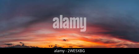 Dramatic sunset sky with clouds. Natural panorama of sky with setting sun. Stock Photo