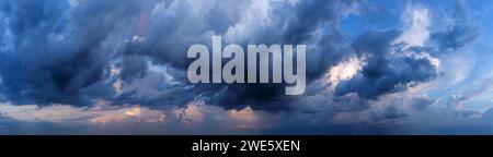 Dramatic sky background with dark rainy clouds at sunset. Stock Photo